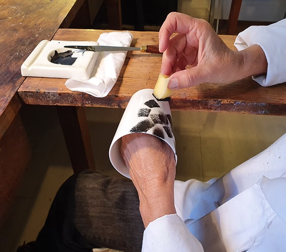 Artisan d’art décorant à la main une pièce en porcelaine